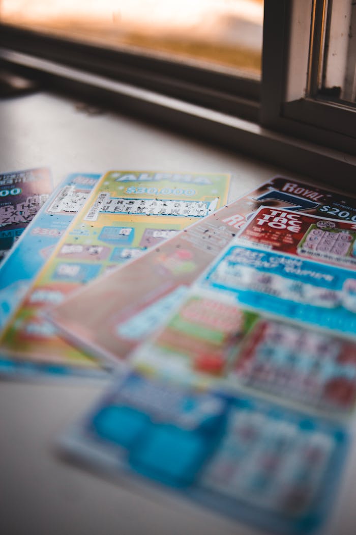 Vivid close-up of assorted lottery tickets on a table near a window, showcasing gambling concepts.